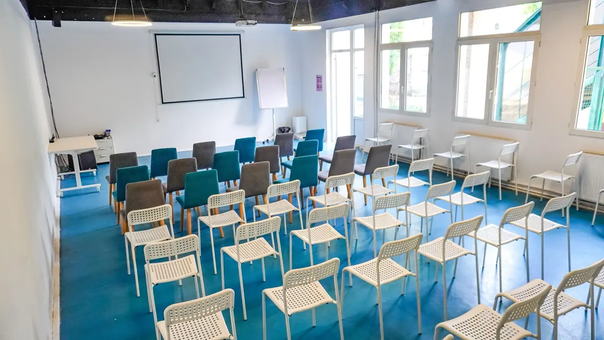 Agora — sala mare de la The Youth, cu scaune și ecran de proiecție